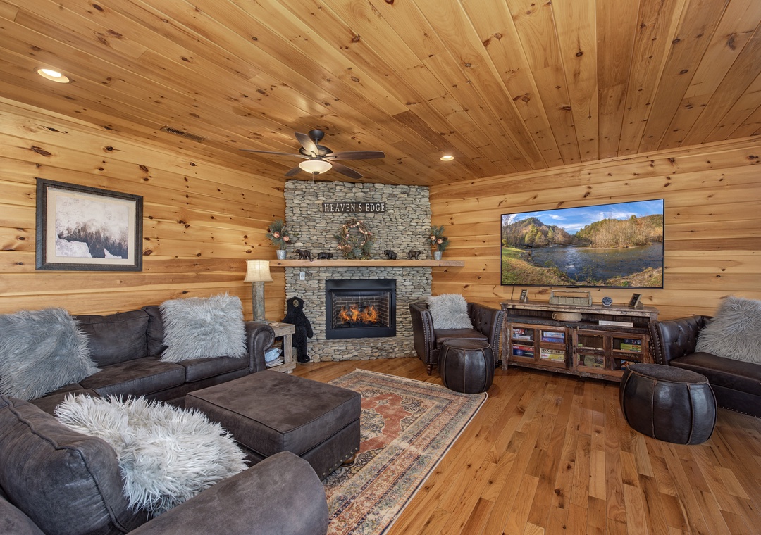 Picture yourself unwinding here—sink into plush sofas, watch flames dance in the stone fireplace, and enjoy mountain views on the big screen. Warm wood surrounds you in total comfort.