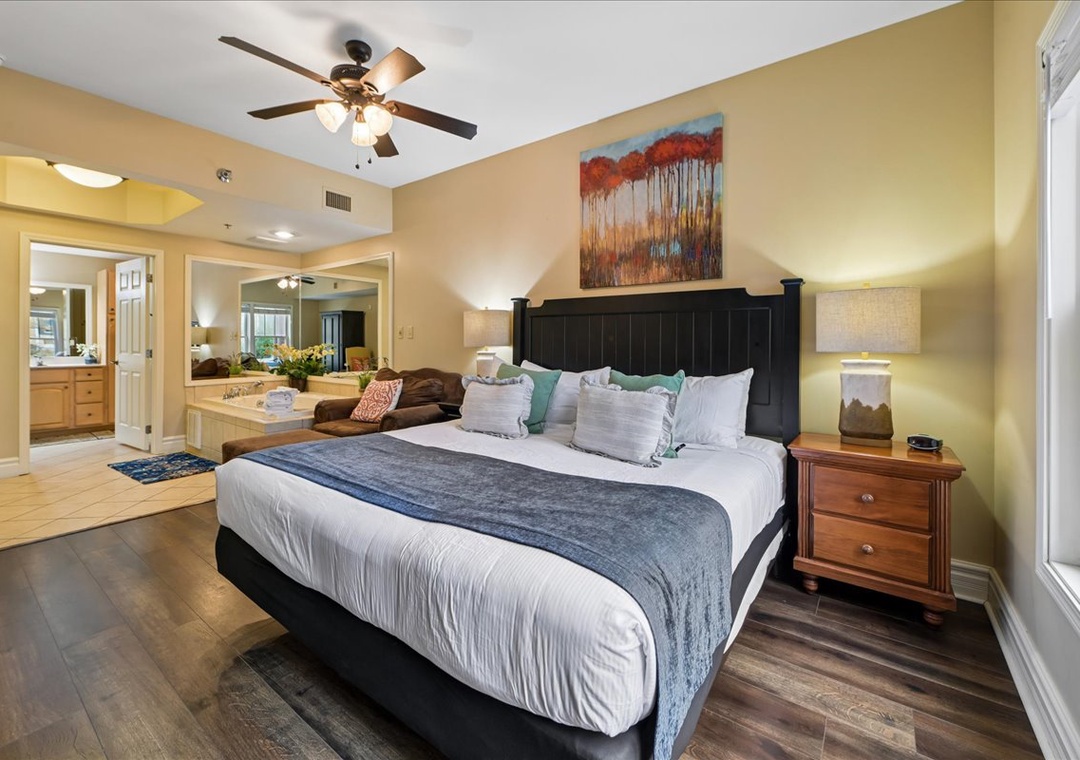 Unwind in your spacious bedroom featuring a plush king bed, ceiling fan, and warm lighting that creates the perfect retreat for relaxation.