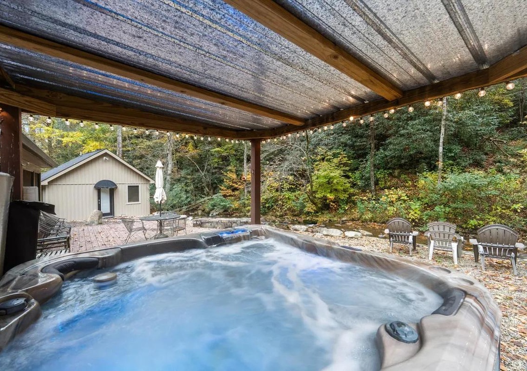 Sink into your private hot tub under twinkling string lights, surrounded by peaceful woods. The covered patio keeps you cozy rain or shine while you soak away the day.