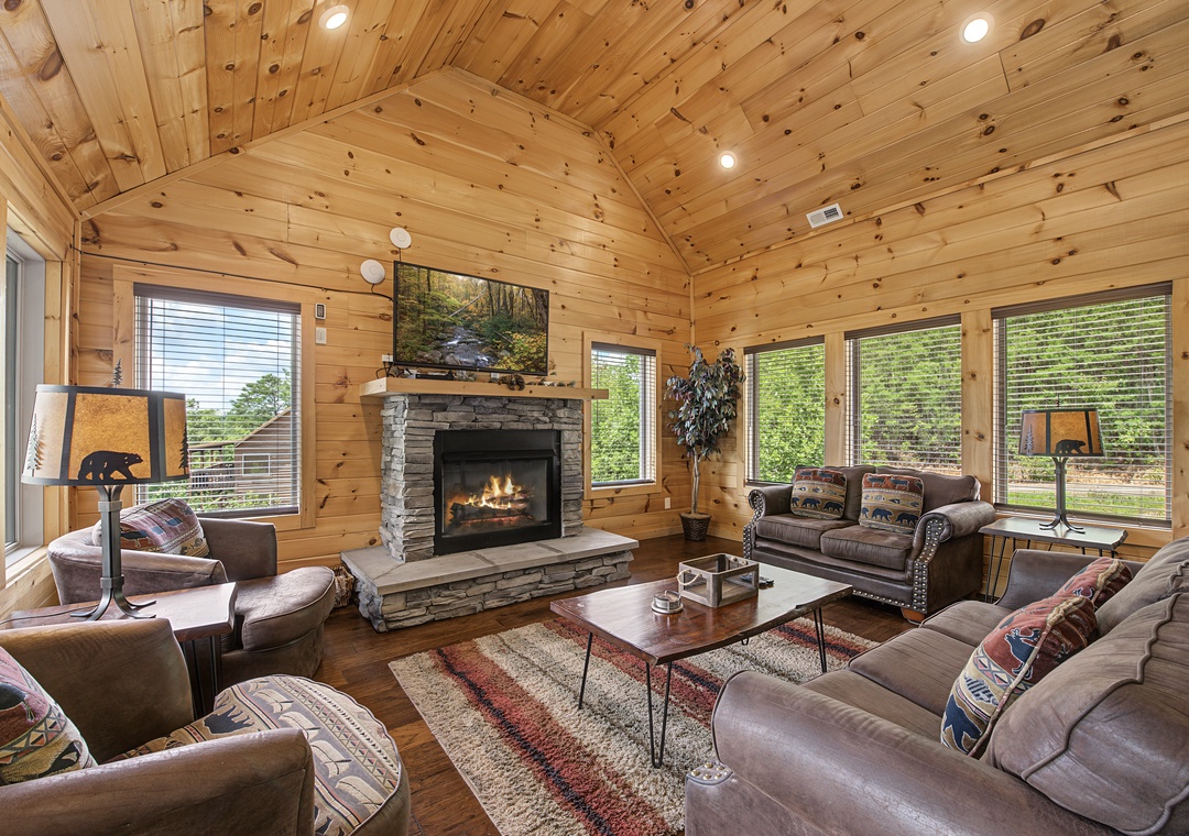 Settle into your cozy retreat surrounded by warm knotty pine and rich leather furnishings, where a crackling stone fireplace anchors the space and floor-to-ceiling windows frame peaceful woodland views on all sides.