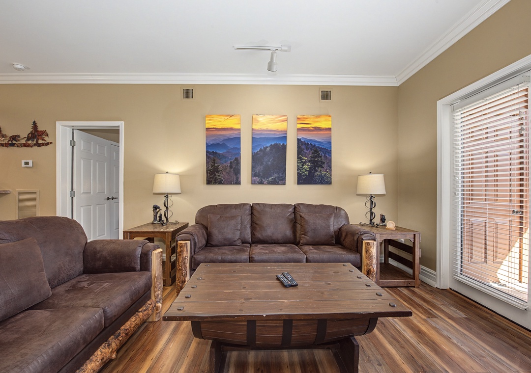 Unwind in your cozy living room with plush leather seating, rustic wood touches, and mountain artwork creating the perfect retreat atmosphere.