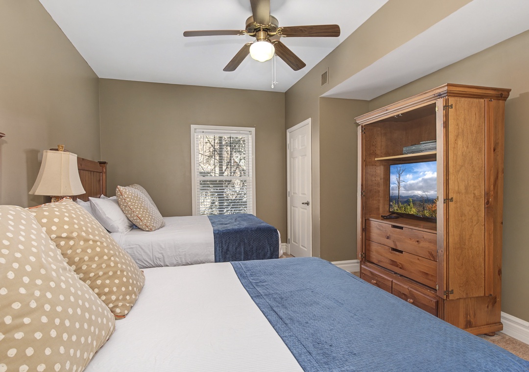 Unwind in your cozy twin bedroom, where soft linens, warm wood furnishings, and a ceiling fan create the perfect retreat.