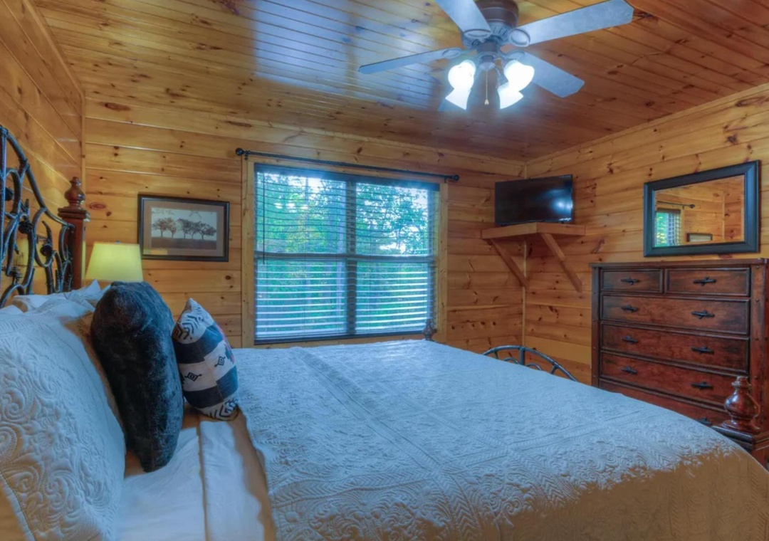 Drift into restful nights in your cozy cabin bedroom, where natural wood walls create warmth and a ceiling fan keeps you comfortable year-round.