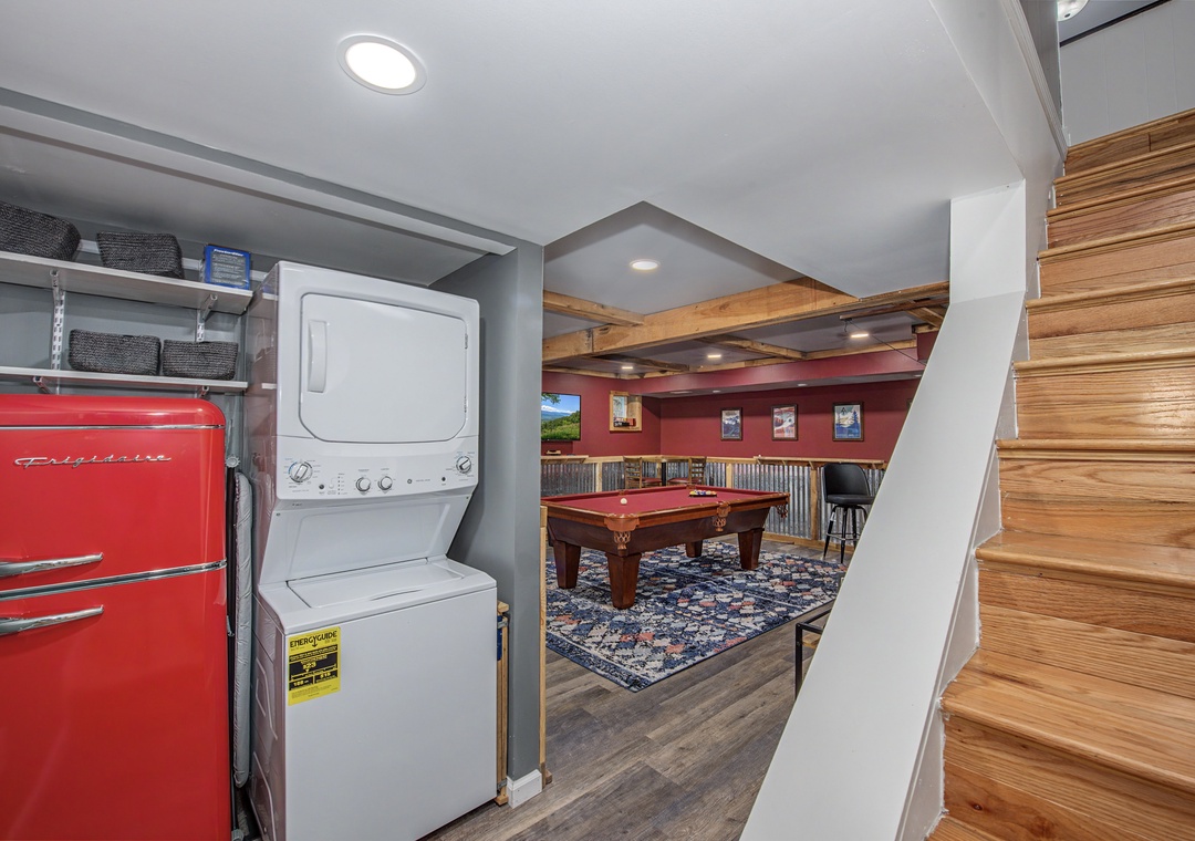 A compact laundry nook with stackable washer-dryer opens to a game room with billiards, offering convenient amenities for your stay.