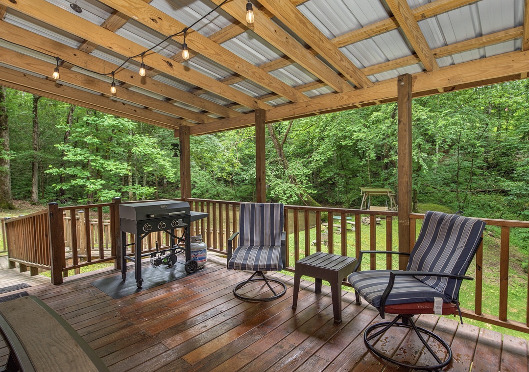 Your private covered deck overlooks lush woods—enjoy morning coffee or evening BBQ in this peaceful, nature-filled retreat with comfortable seating.