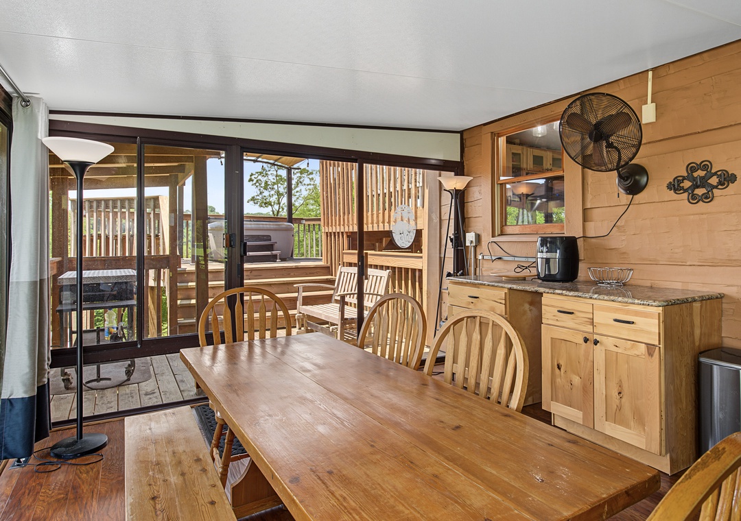 Gather around this inviting wooden dining table where you can share meals and stories. The space opens onto your private deck, blending indoor comfort with fresh outdoor air for a relaxing retreat.