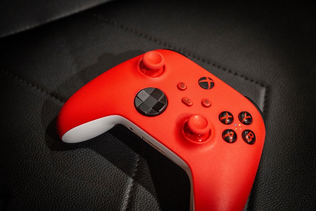 The vibrant red gaming controller sits ready on sleek black leather, inviting you to unwind with your favorite games after a day exploring the area.