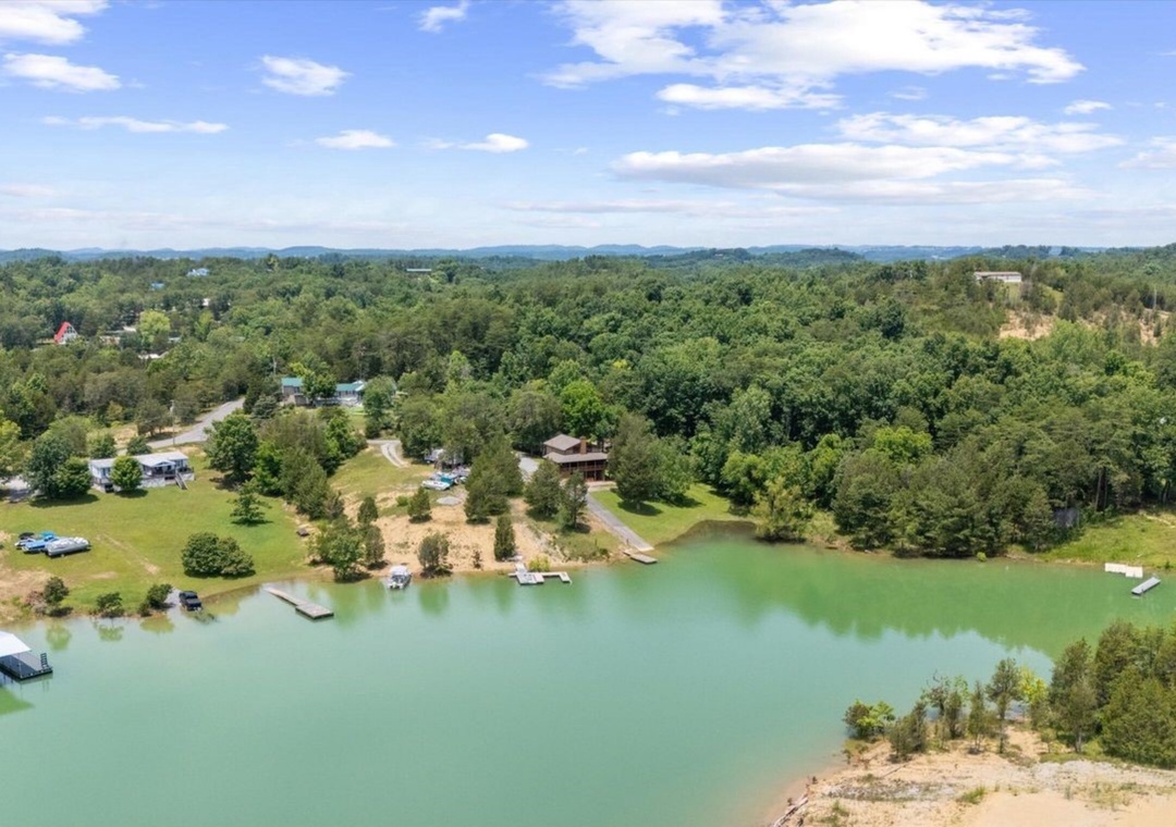 Aerial view of peaceful lakefront community with private docks, wooded surroundings, and scenic waterfront homes nestled among rolling hills.