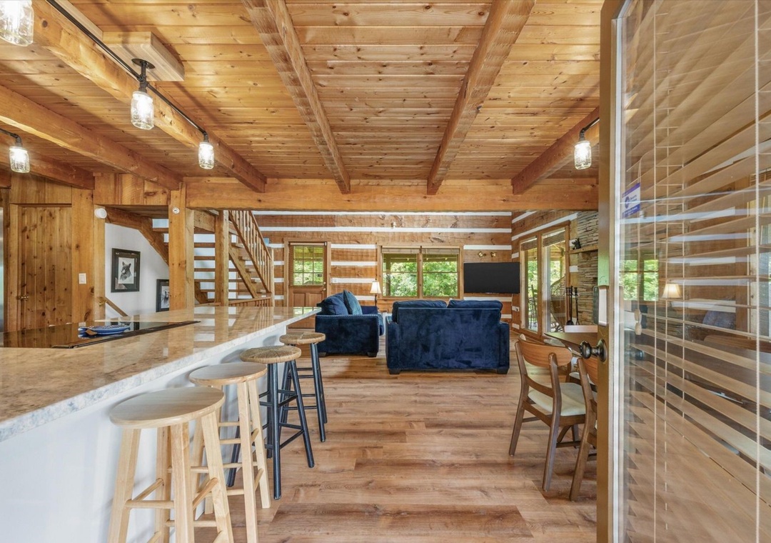 Settle into this stunning log cabin's open-concept space where rustic charm meets modern comfort. You'll love gathering around the kitchen island.