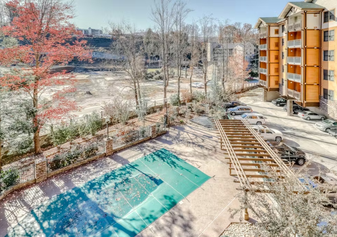 Elevated view showcasing the property's outdoor swimming pool area, parking facilities, and surrounding autumn landscape with colorful foliage.