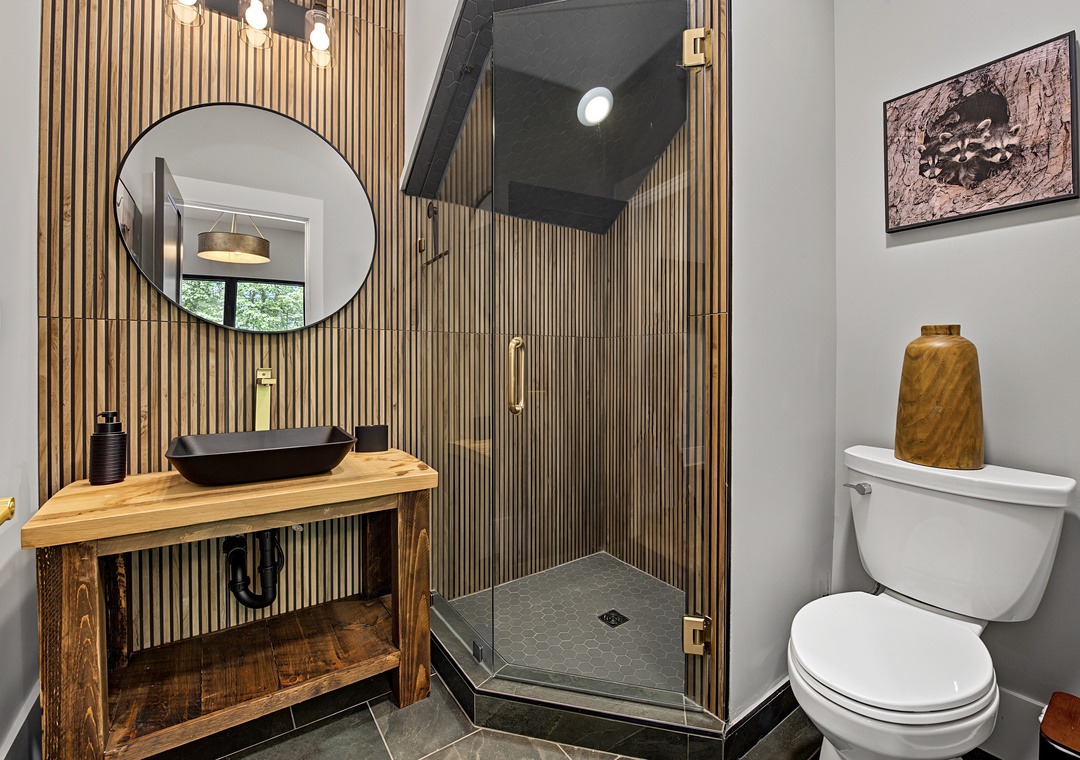 Refresh after your adventures in this modern bathroom with sleek fixtures, natural wood accents, a spacious walk-in shower, and thoughtful design touches that blend comfort with style.