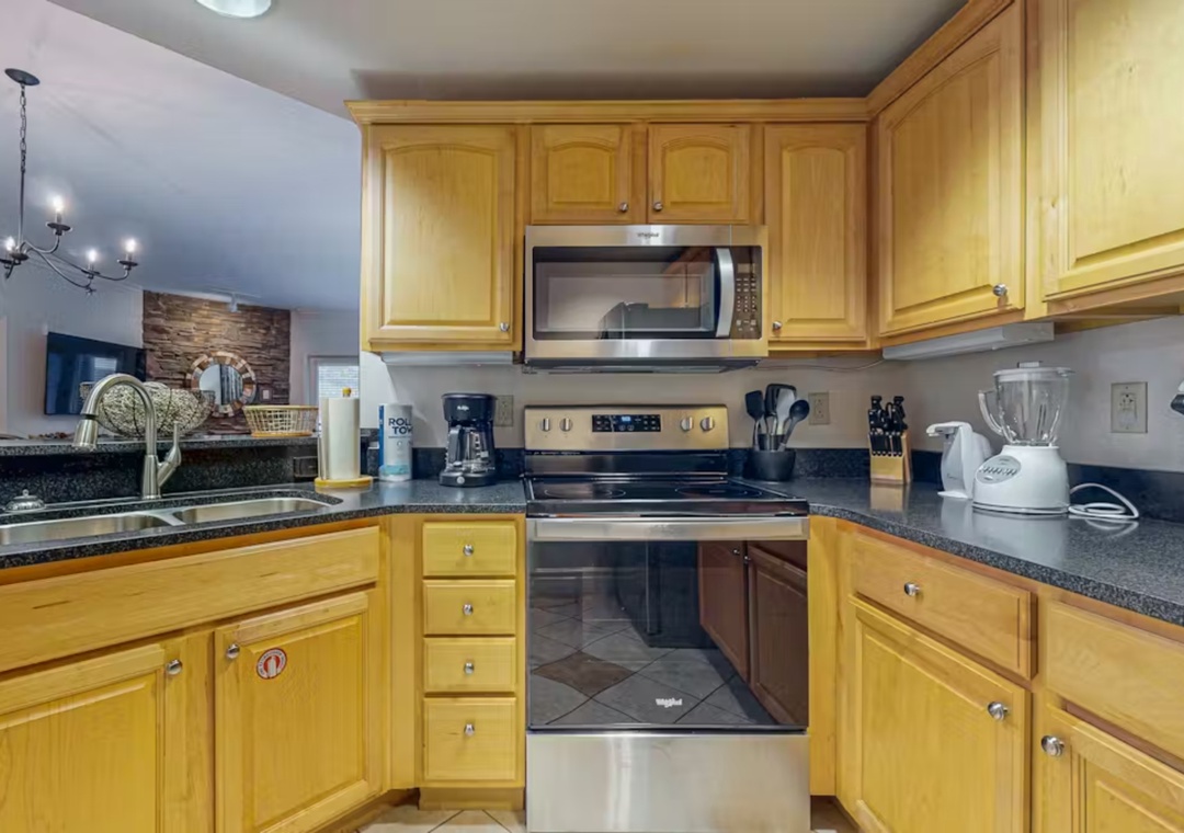 Your fully equipped kitchen awaits with warm wood cabinets, granite counters, and stainless appliances for home-cooked meals.