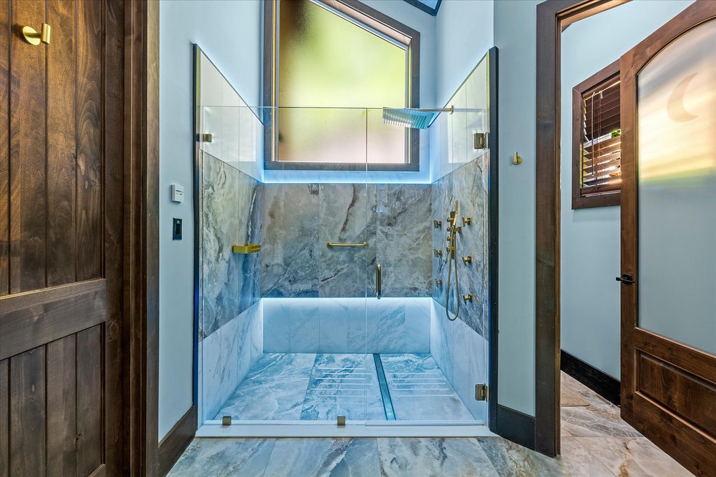 Step into a spa-like sanctuary with gleaming marble surfaces, elegant brass fixtures, and natural light streaming from above. This stunning walk-in shower elevates your daily routine.