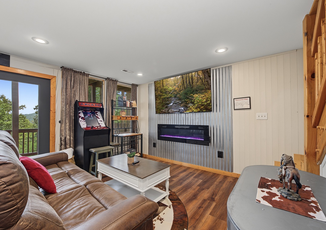 Unwind in your cozy living space with mountain views, an arcade, and modern fireplace—your perfect retreat for fun and relaxation.