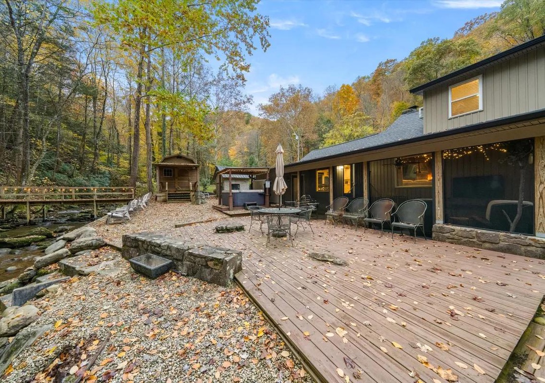 The property sits nestled in a wooded mountain setting, surrounded by vibrant autumn foliage and natural stone features, offering a serene seasonal escape.