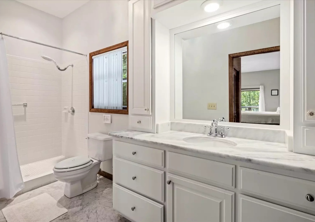 Refresh in your pristine bathroom featuring marble countertops, spacious vanity, and bright natural light from the window.