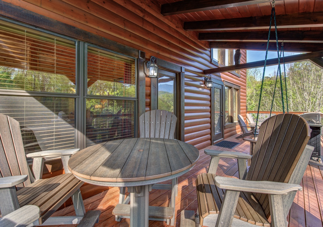 Relax on your private covered deck with rustic wooden furniture and mountain views stretching beyond the trees.