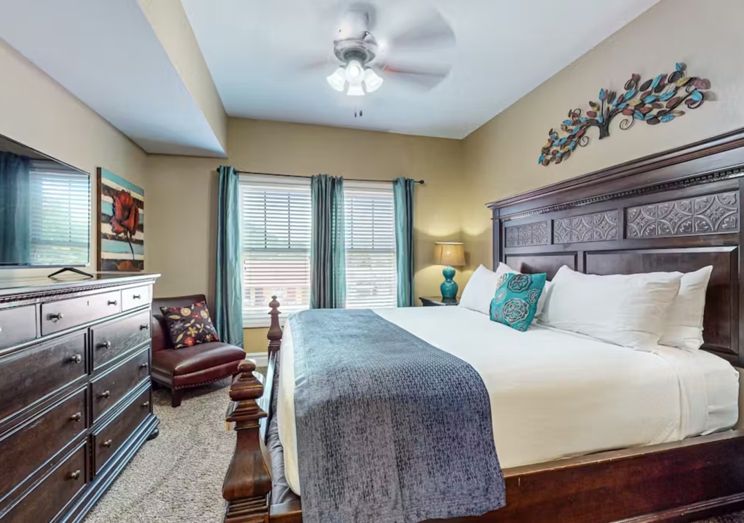 Unwind in your elegant bedroom featuring rich wood furnishings, crisp linens, and soothing turquoise accents that create the perfect retreat.