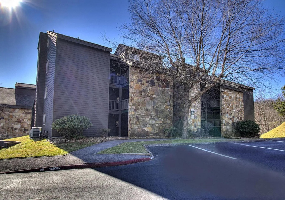 Multi-story stone and wood building with convenient parking and well-maintained landscaping in a peaceful setting.