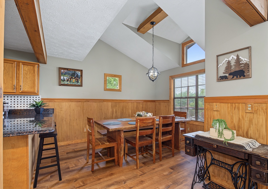 Gather around the cozy dining table under vaulted ceilings with warm wood accents, where natural light streams through the windows and rustic charm meets mountain elegance.