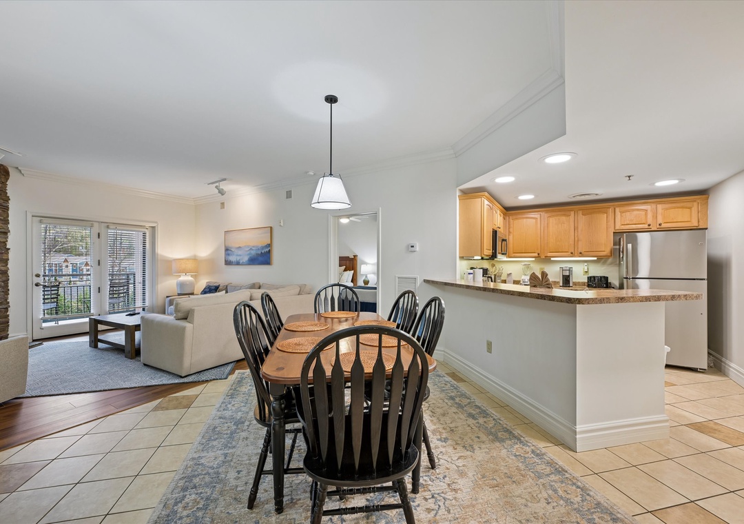 Your open-concept haven seamlessly blends kitchen, dining, and living spaces with warm wood cabinets and city balcony views.