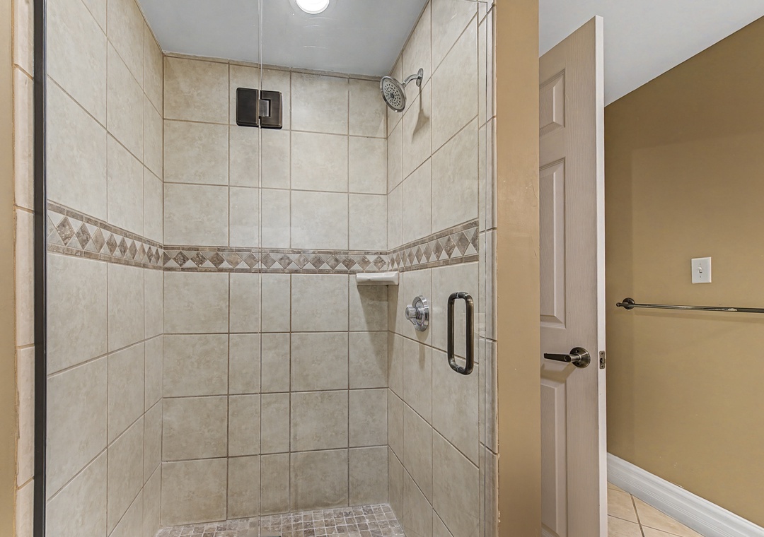 Step into your private spa-style shower with elegant tilework and rainfall showerhead for the perfect start to your day.