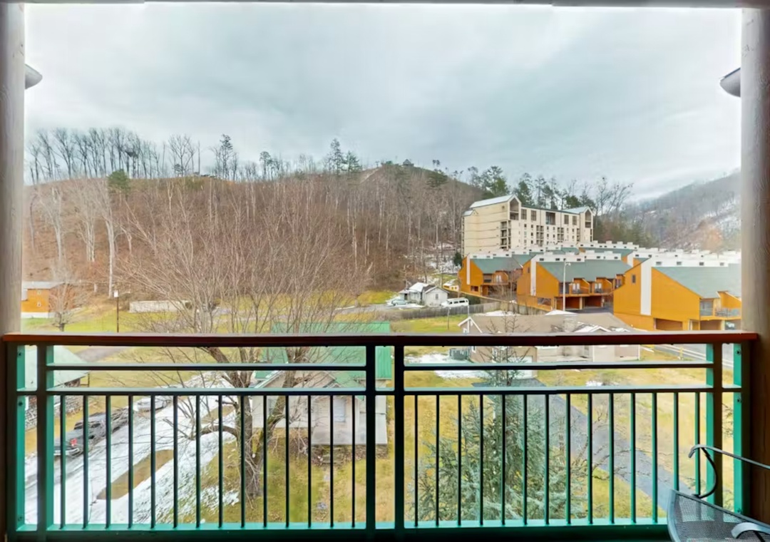Mountain valley views frame colorful resort buildings and rolling hills from this peaceful balcony retreat.