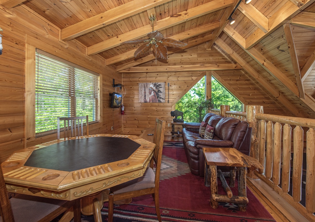 Unwind in your private loft game room with rustic charm, leather seating, and forest views through beautiful windows.