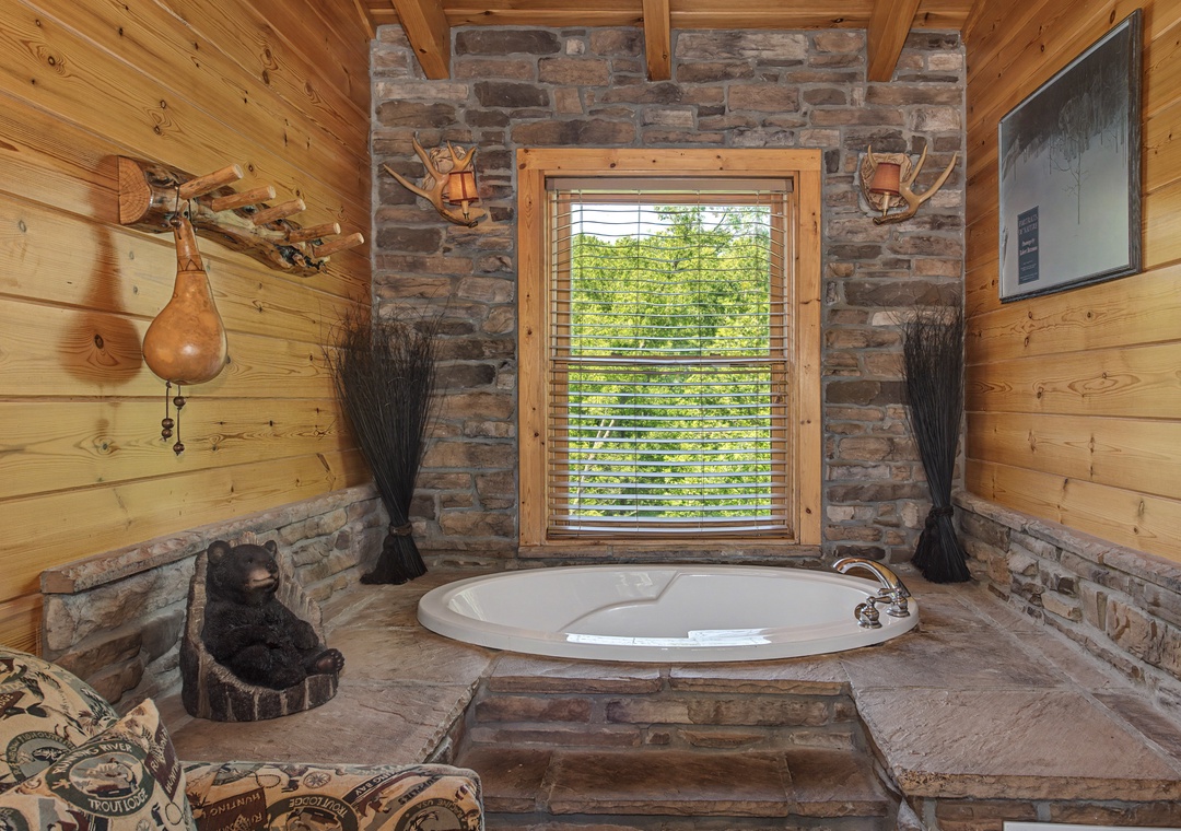 Soak in your private stone-surrounded tub while forest views through rustic cabin windows create the perfect mountain retreat atmosphere.