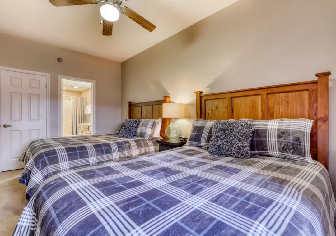 Rest easy in your cozy twin bedroom with rustic wood furnishings and soft plaid bedding that invites peaceful sleep.