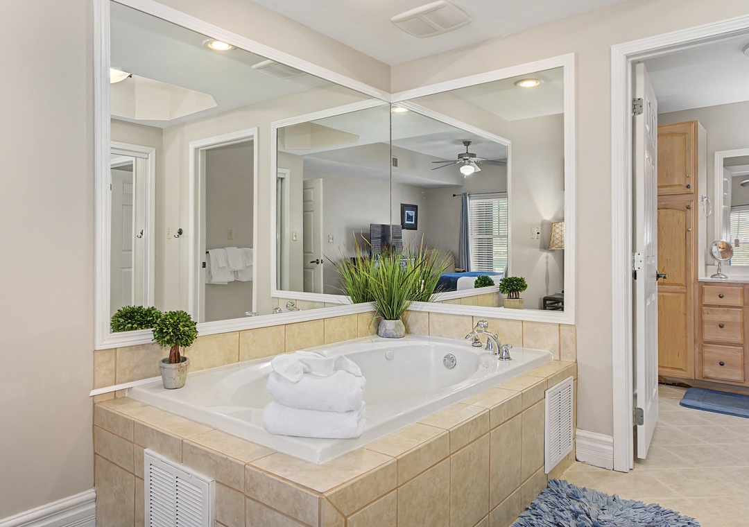 Unwind in your luxurious bathroom sanctuary with a spacious soaking tub surrounded by mirrors and fresh towels for ultimate relaxation.