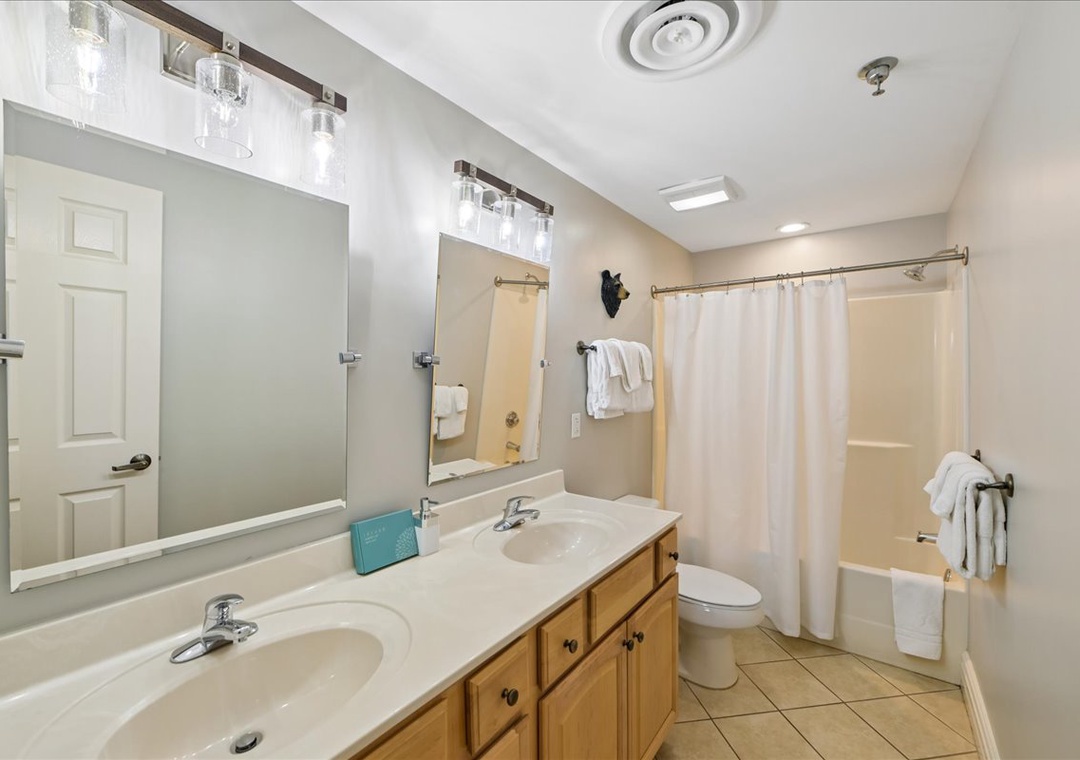 Your spacious bathroom features dual sinks with modern lighting, a relaxing tub-shower combo, and fresh towels waiting for you.