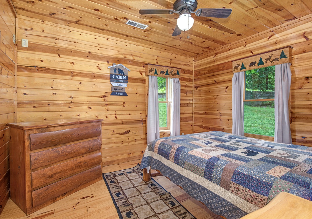Cozy log cabin bedroom with handcrafted wooden furnishings, rustic wildlife decor, and peaceful garden views inviting you to unwind in nature's embrace.