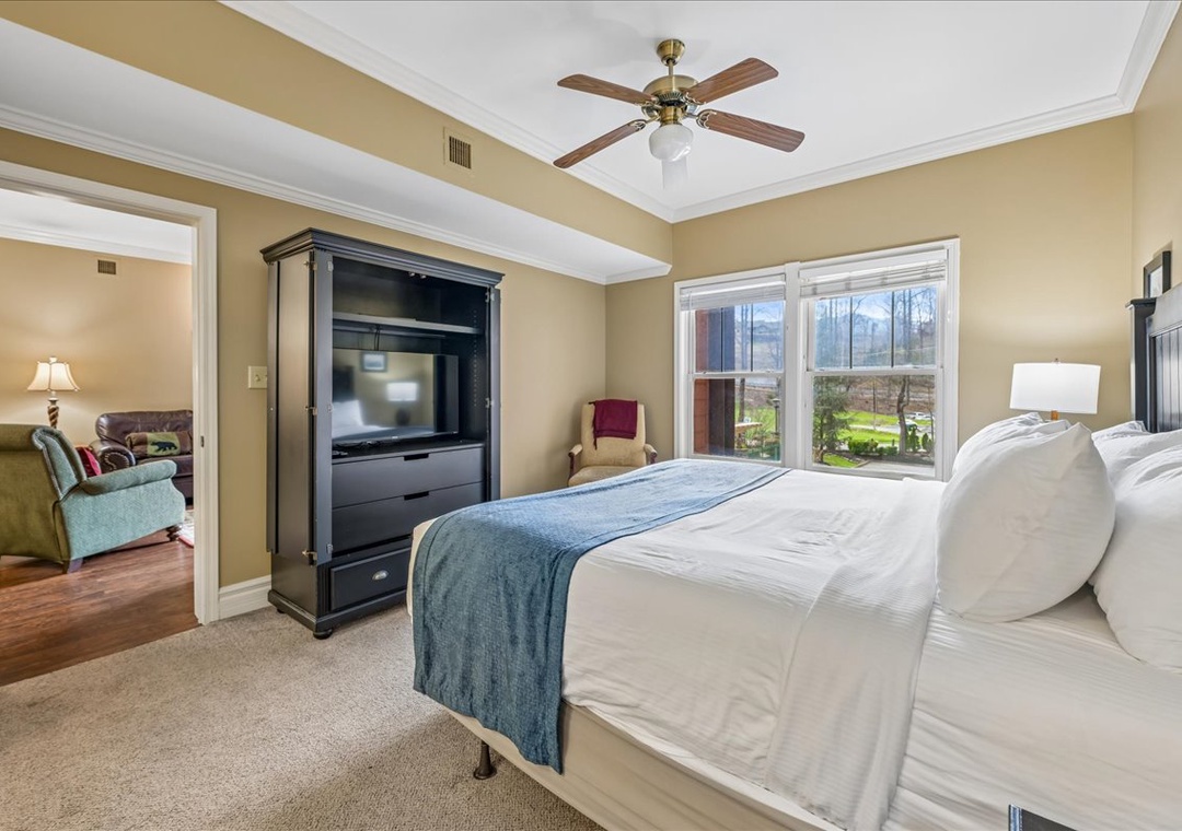 Your master bedroom offers crisp linens, garden views, and entertainment comfort with TV and ceiling fan for perfect relaxation.