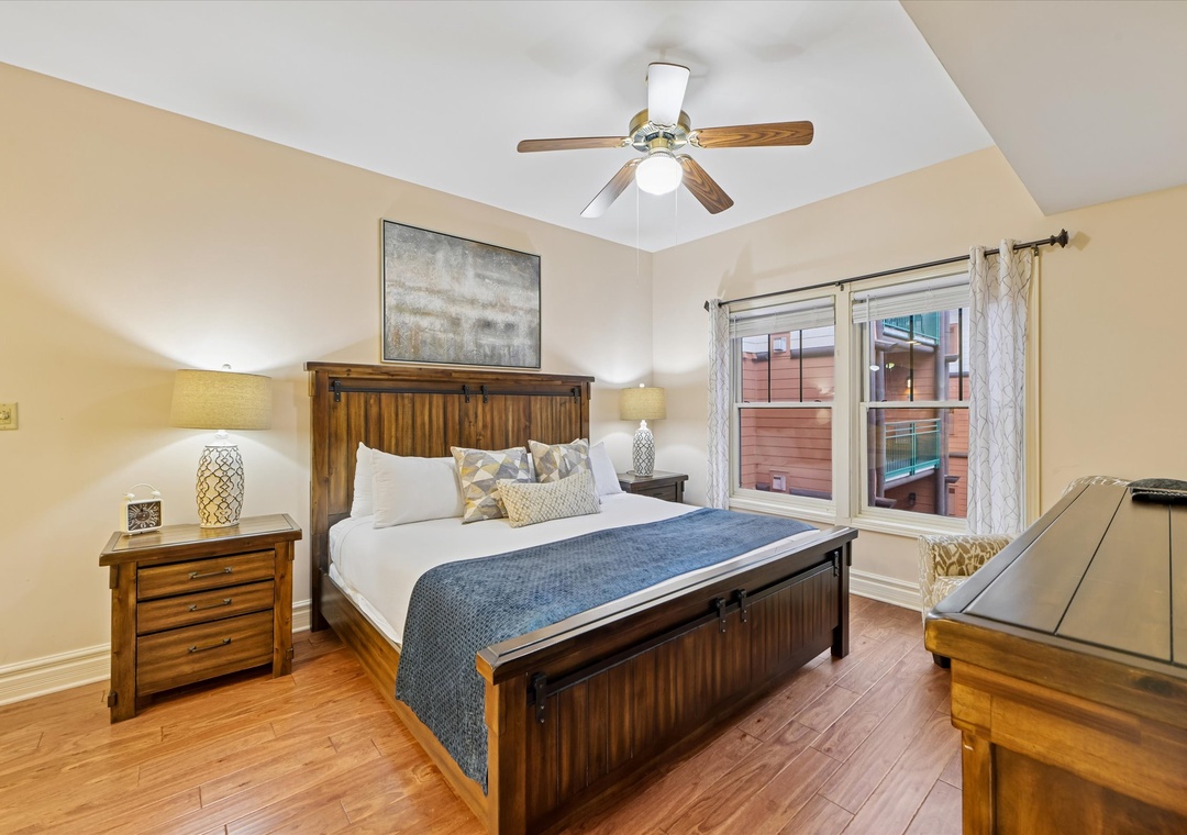 Unwind in your serene bedroom with rustic wood furnishings, crisp linens, and gentle ceiling fan creating the perfect restful retreat.