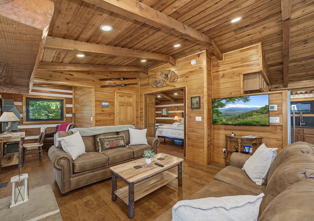 Sink into plush sofas beneath vaulted wood ceilings in your cozy cabin retreat, where warm lighting and rustic charm create the perfect setting for unwinding after mountain adventures.