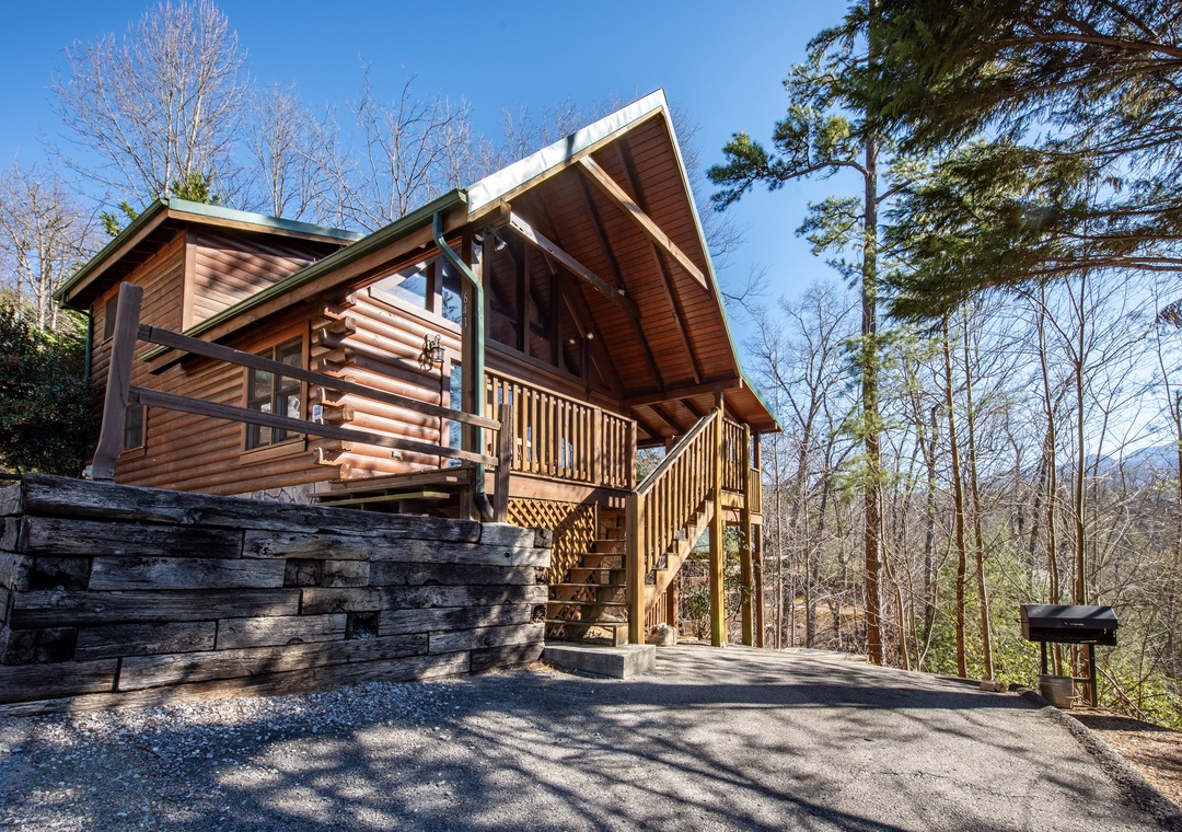 Modern log cabin nestled in wooded mountain setting with stone accents and expansive covered deck.