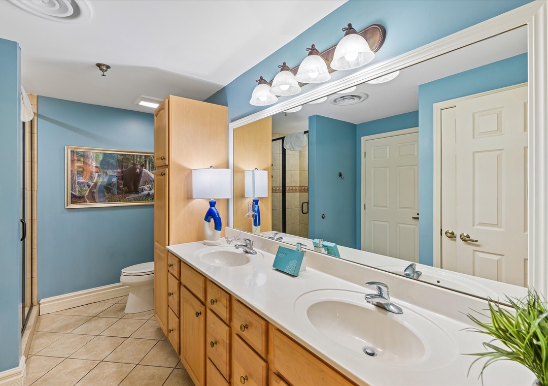 Spacious bathroom with dual sinks, ample counter space, and warm wood cabinetry for your morning routines together.