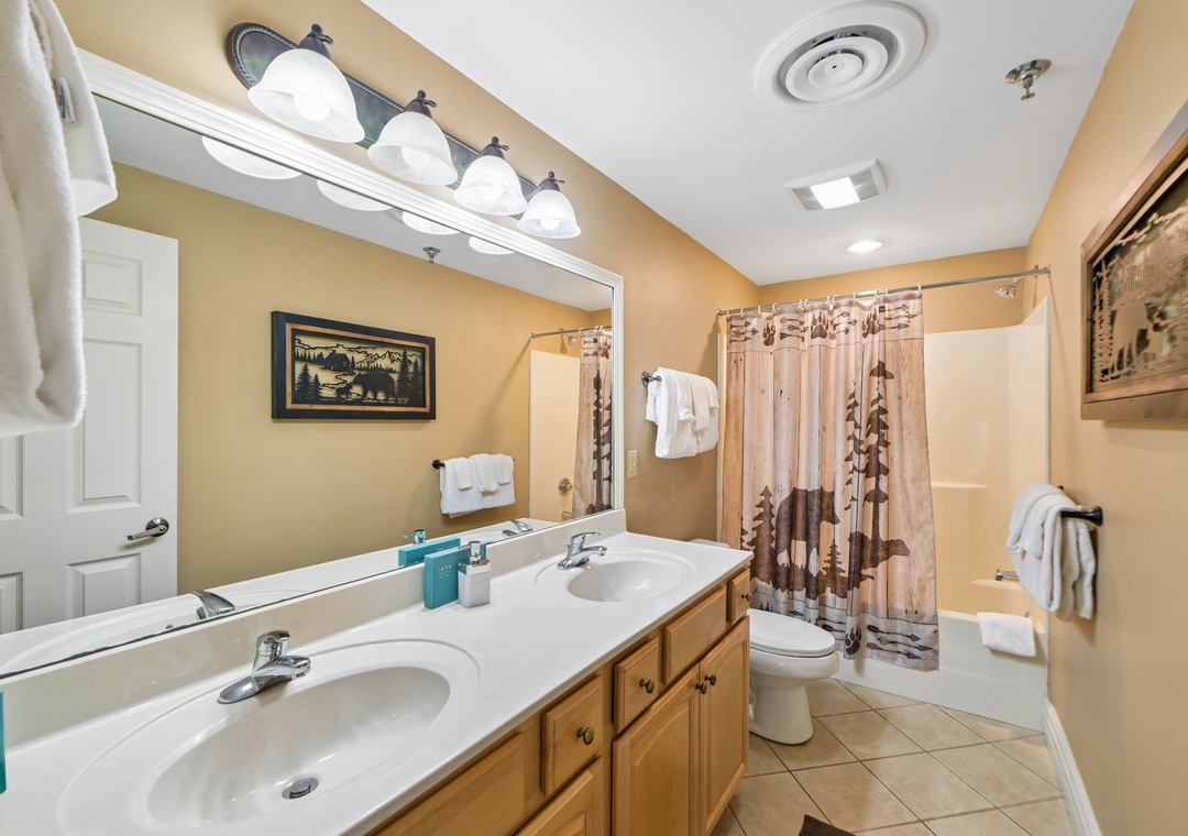 You'll love the spacious bathroom with dual sinks, warm lighting, and nature-themed touches that create a welcoming retreat for your morning routine.