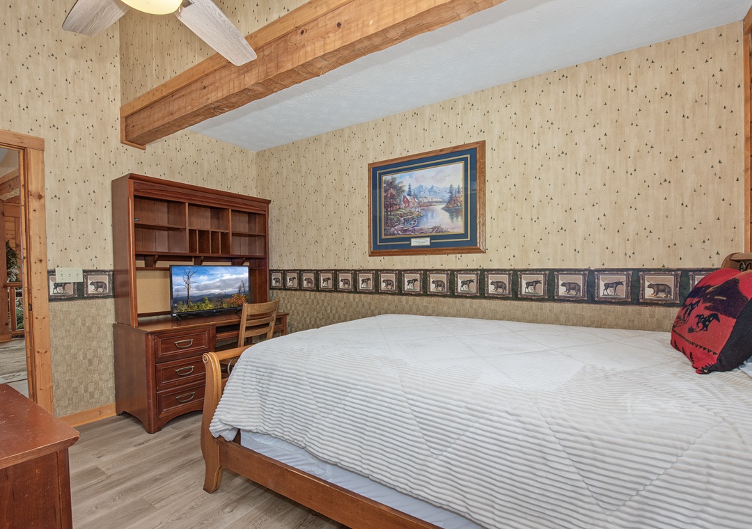 Drift off in your rustic-chic retreat, where exposed wood beams and a cozy ceiling fan set the scene for mountain dreams. Your comfortable bed awaits beneath vaulted ceilings that echo the charm of a woodland lodge.