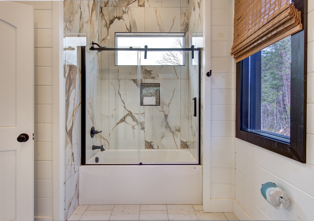 Luxurious spa-inspired bathroom with stunning marble shower and serene forest views through your private window.