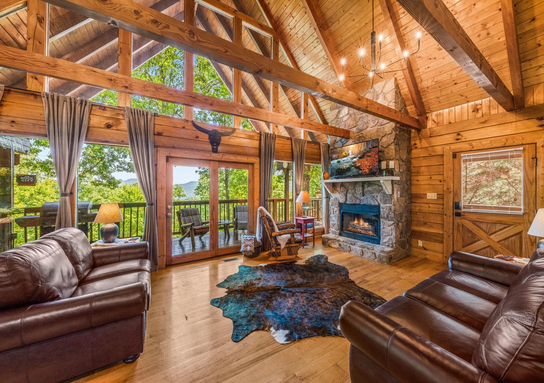 Picture yourself here: sprawling on rich leather sofas beneath soaring wood beams, fire crackling softly, while sunlight pours through towering windows framing lush mountain views—your perfect retreat awaits.