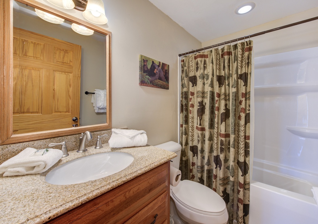 Step into your private bathroom featuring warm wood finishes, granite countertops, and charming rustic décor that makes every morning feel cozy.