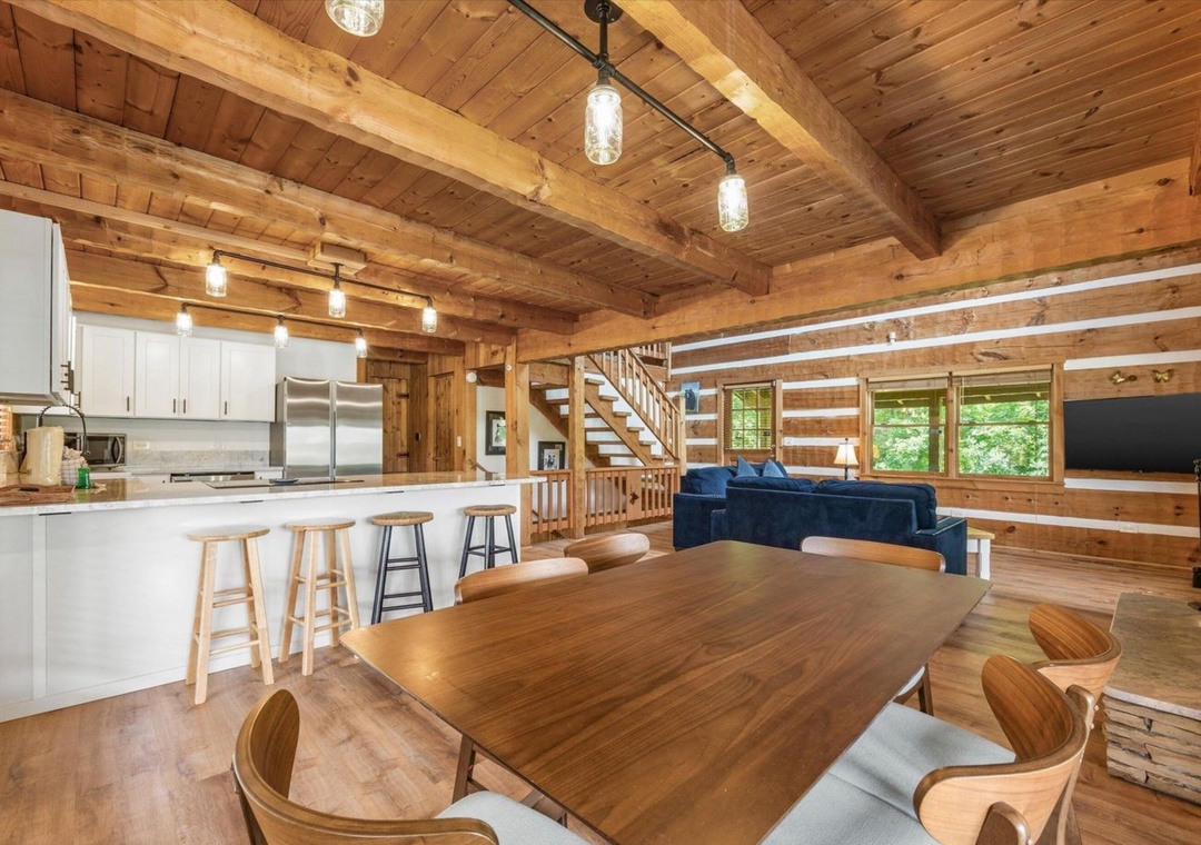 Gather around the stunning wood dining table in this open-plan cabin where rustic beams meet modern comfort perfectly.