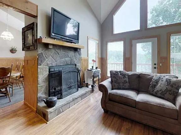 Sink into the plush sofa and enjoy the warmth of your wood-burning fireplace beneath vaulted ceilings. Natural light floods the space through expansive windows overlooking the scenic outdoors.