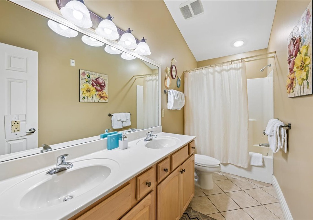 Freshen up in your spacious bathroom with double vanity, tub-shower combo, and cheerful floral artwork.