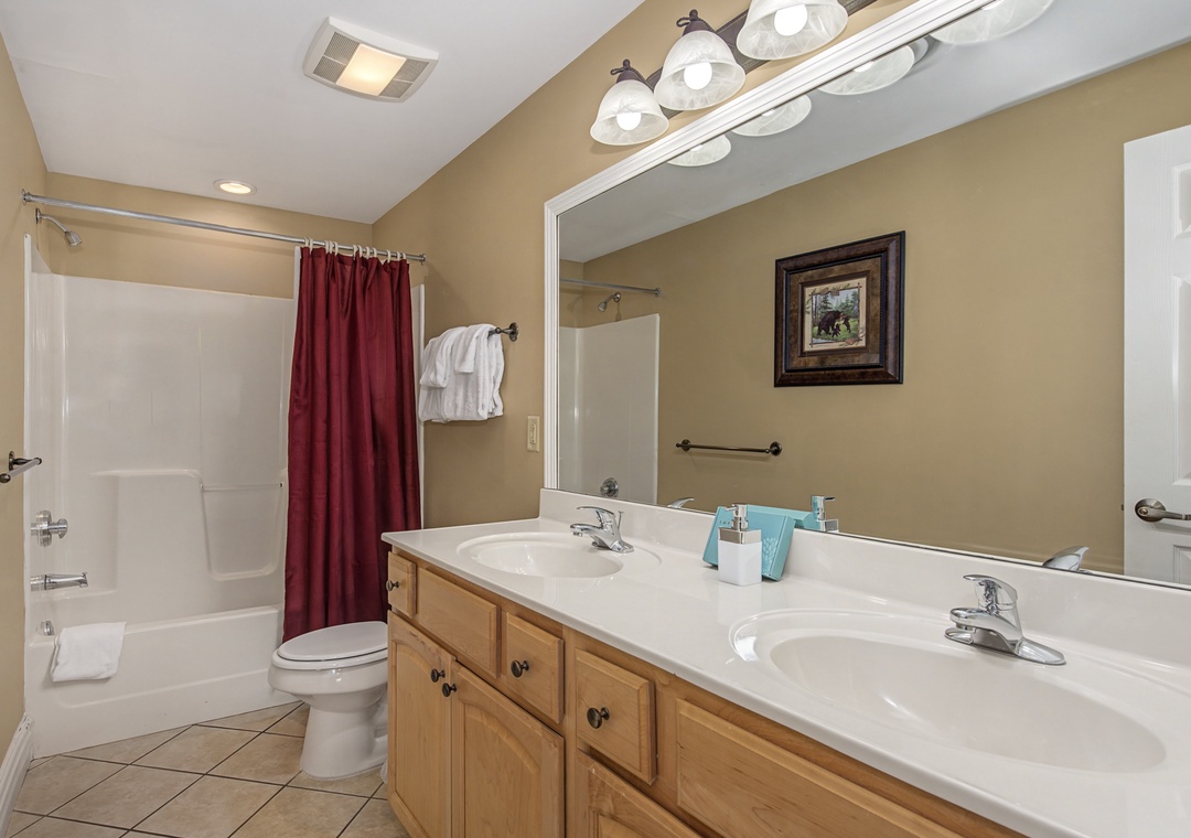 Step into your spacious bathroom featuring dual sinks, warm wood cabinetry, and a relaxing tub-shower combo for refreshing mornings.