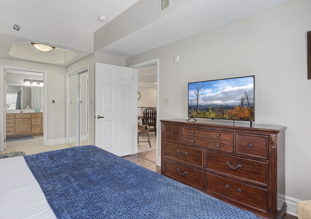 Relax in your spacious bedroom with mountain views on the flat-screen TV, elegant wooden dresser, and easy bathroom access.