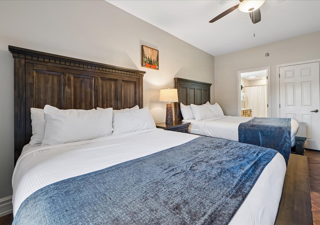 Rest peacefully in your spacious bedroom with two comfortable beds, elegant wood headboards, and thoughtful touches like bedside lighting.