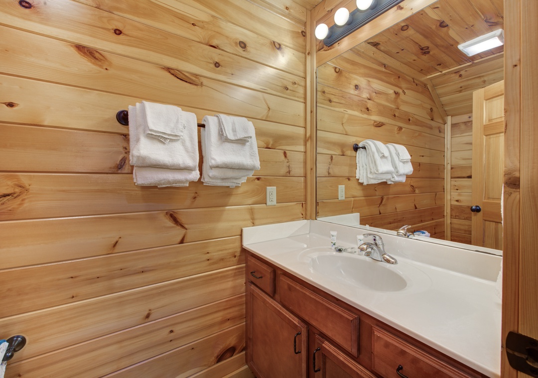 Wrap yourself in the soft, fluffy towels that await you in your cabin's cozy bathroom, where natural wood walls create a warm, inviting retreat after a day of adventure.